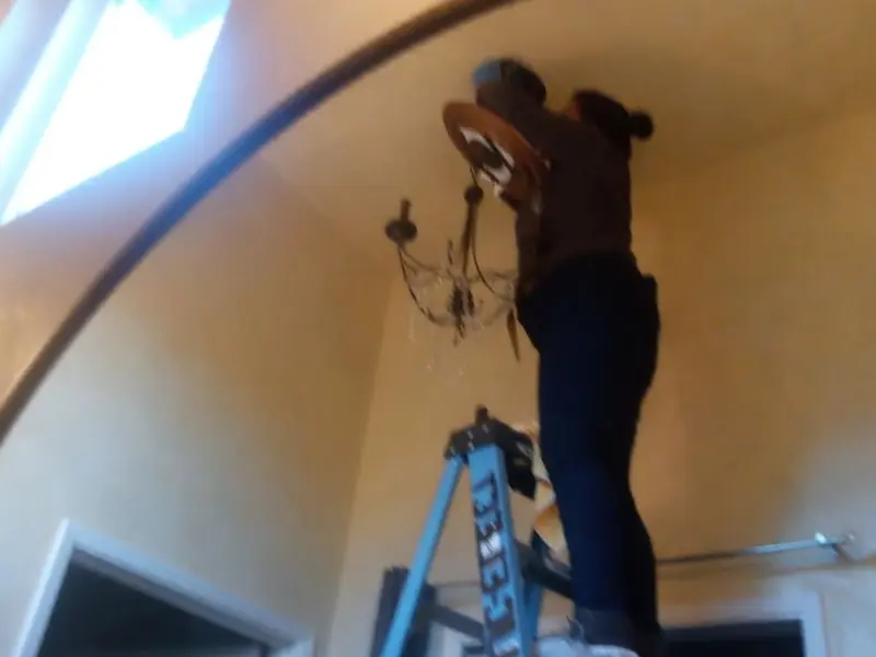 Electrician installing a chandelier in a Lower Alsace residence